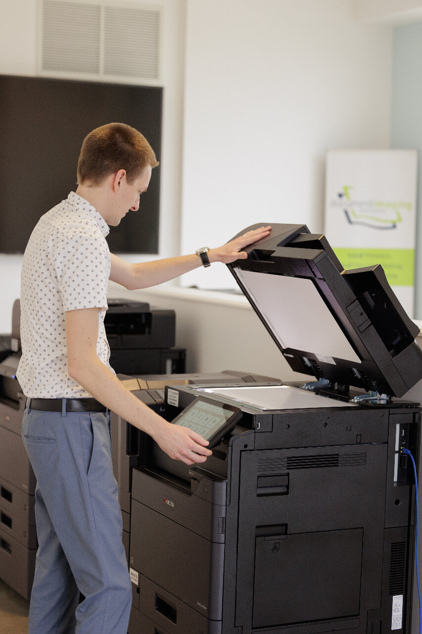 Service Technician looking at Kyocera Multifunction printer with document cover raised